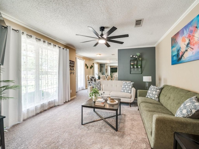 living area featuring a textured ceiling, visible vents, ceiling fan, ornamental molding, and carpet