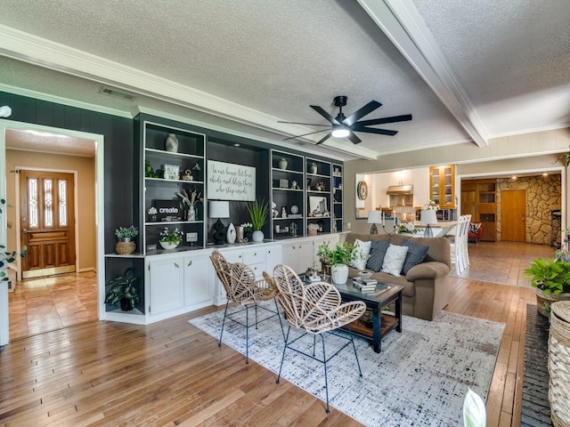 living area featuring crown molding, a ceiling fan, visible vents, a textured ceiling, and hardwood / wood-style floors