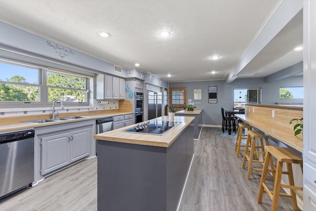 kitchen featuring wood counters, appliances with stainless steel finishes, a kitchen island, a sink, and visible vents