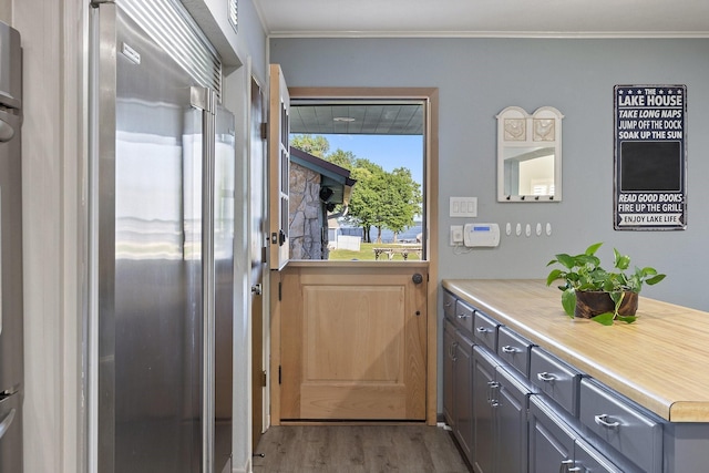 doorway to outside featuring wood finished floors and ornamental molding
