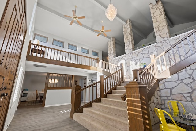 staircase featuring visible vents, beam ceiling, wood finished floors, a ceiling fan, and high vaulted ceiling