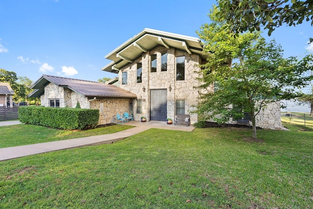 view of front of property featuring fence, metal roof, a front lawn, and stone siding