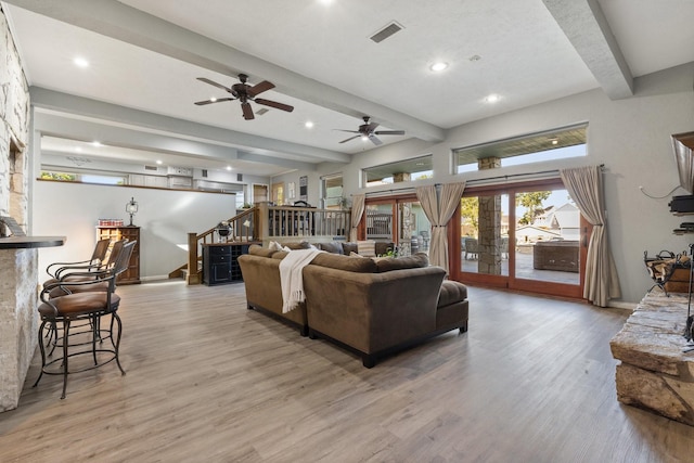 living room with beamed ceiling, stairway, ceiling fan, visible vents, and light wood-style flooring