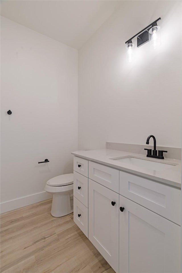 bathroom featuring wood finished floors, vanity, toilet, and baseboards