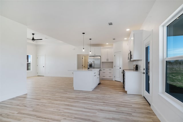 kitchen featuring stainless steel appliances, light wood-style floors, open floor plan, and light countertops