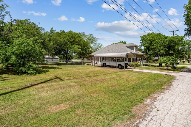 view of yard with fence, driveway, and a detached carport