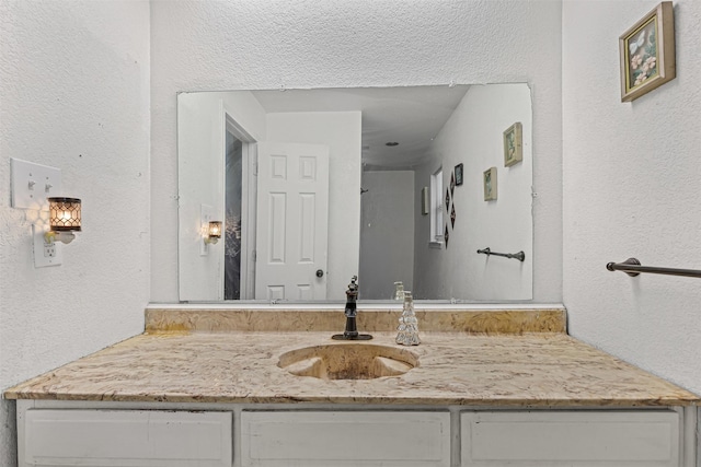 bathroom featuring a textured wall and vanity