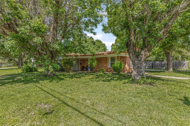 ranch-style house featuring a front yard, brick siding, and fence