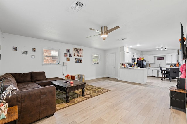 living area with visible vents, light wood-type flooring, and a ceiling fan
