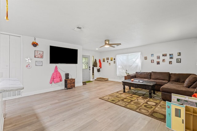 living area featuring visible vents, light wood-type flooring, a ceiling fan, and baseboards