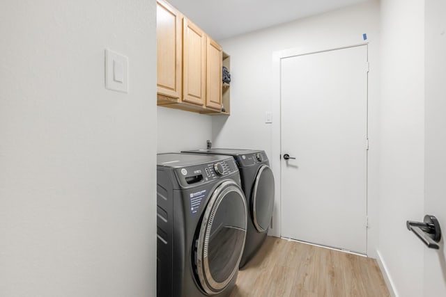 laundry room featuring separate washer and dryer, cabinet space, and light wood-style floors
