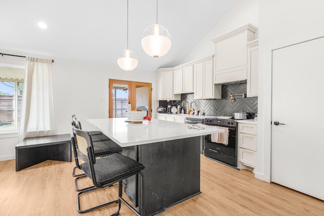 kitchen with decorative backsplash, light wood-style floors, black / electric stove, and white cabinets