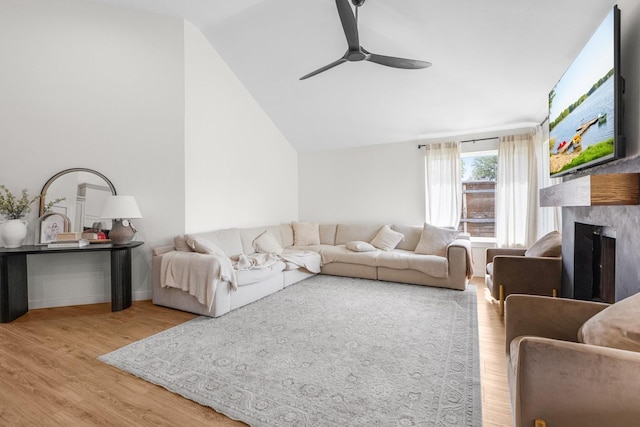 living area featuring wood finished floors, a ceiling fan, a premium fireplace, and lofted ceiling