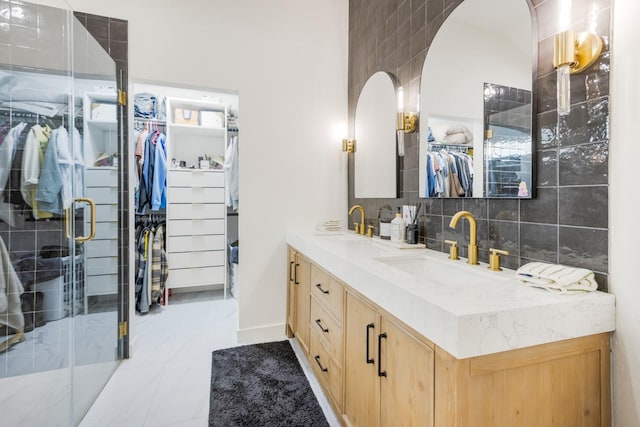 full bathroom featuring decorative backsplash, a sink, double vanity, a stall shower, and a walk in closet