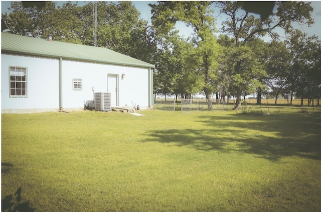 view of yard with central AC and fence