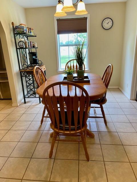 dining space featuring light tile patterned floors, baseboards, and arched walkways