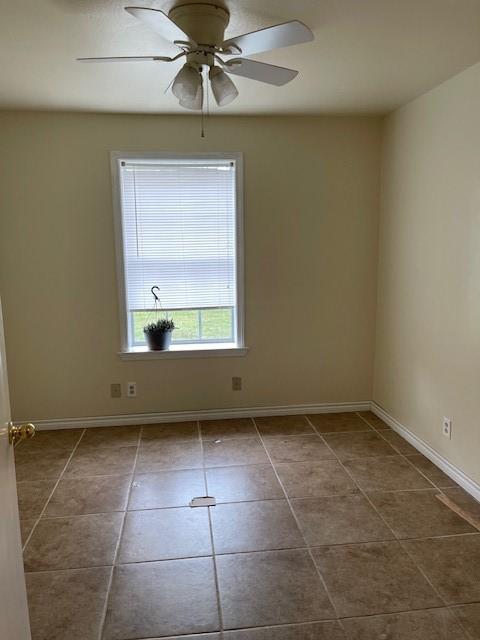 empty room with baseboards, tile patterned flooring, and a ceiling fan