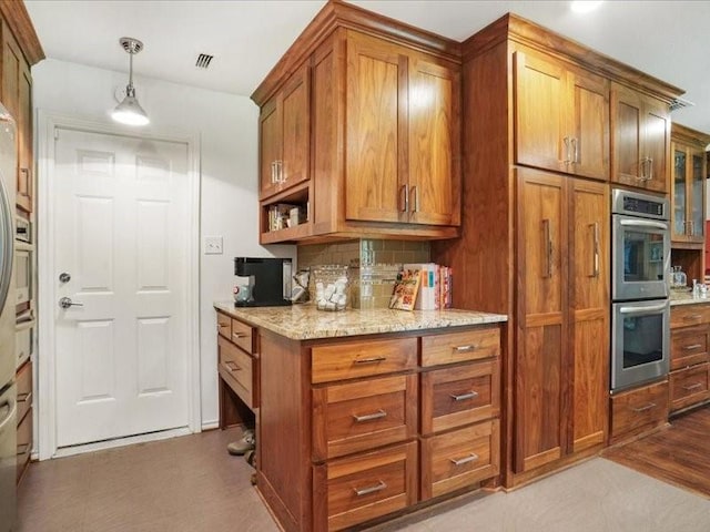 1428 Oxford Ln, Denton, TX 76209 - kitchen with double oven, brown cabinetry, decorative backsplash, and light stone countertops