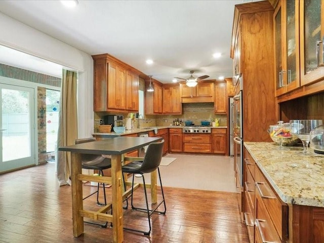 1428 Oxford Ln, Denton, TX 76209 - kitchen featuring light wood-style floors, stainless steel gas cooktop, brown cabinetry, and a ceiling fan
