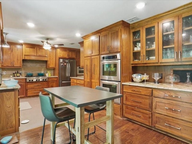 1428 Oxford Ln, Denton, TX 76209 - kitchen featuring visible vents, ceiling fan, brown cabinets, tasteful backsplash, and stainless steel appliances