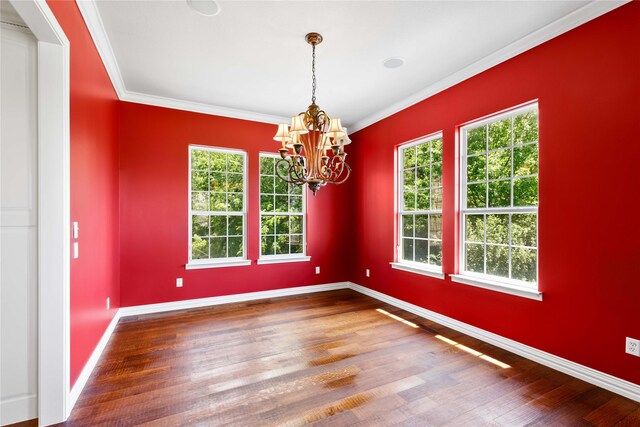 spare room featuring wood finished floors, a notable chandelier, and ornamental molding