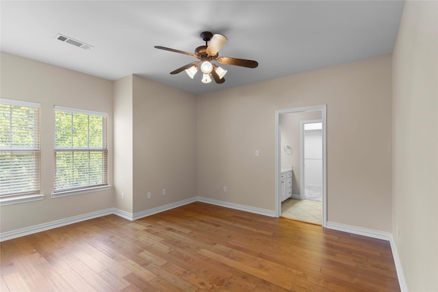 spare room with baseboards, visible vents, a ceiling fan, and light wood-style floors