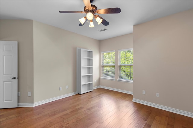 spare room with baseboards, visible vents, wood finished floors, and a ceiling fan