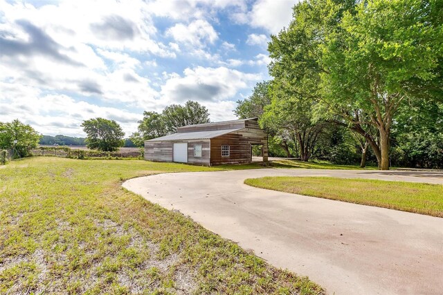 view of side of home featuring a lawn and curved driveway
