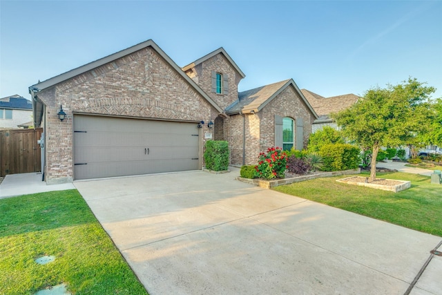 view of front of house with a front yard, brick siding, concrete driveway, an attached garage, and fence