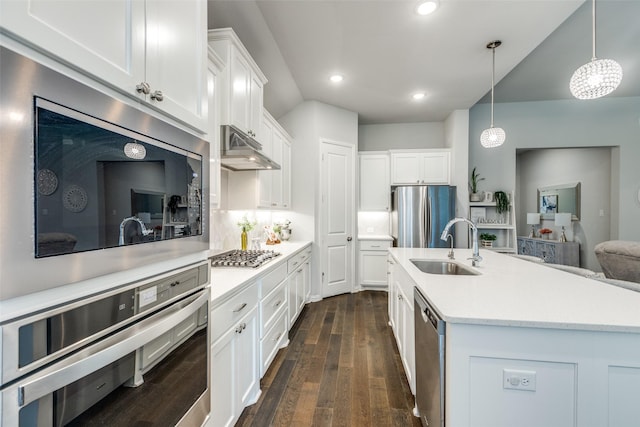 kitchen featuring a sink, stainless steel appliances, under cabinet range hood, light countertops, and dark wood finished floors