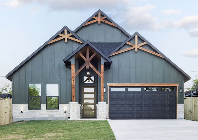 view of front facade featuring driveway, board and batten siding, stone siding, an attached garage, and fence