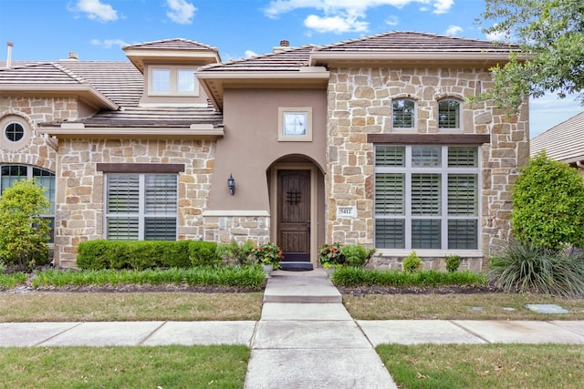 view of front of home featuring stucco siding, a tiled roof, and stone siding