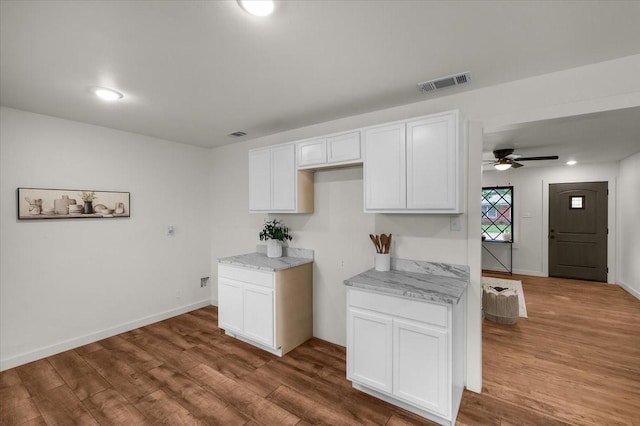 5409 Mallory Dr, Haltom City, TX 76117 - kitchen with light stone counters, white cabinetry, visible vents, ceiling fan, and wood finished floors