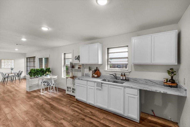 5409 Mallory Dr, Haltom City, TX 76117 - kitchen with recessed lighting, light stone countertops, a sink, white cabinetry, and wood finished floors