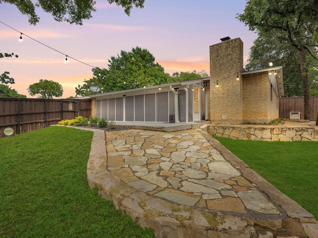 view of yard with a patio, a fenced backyard, and a sunroom