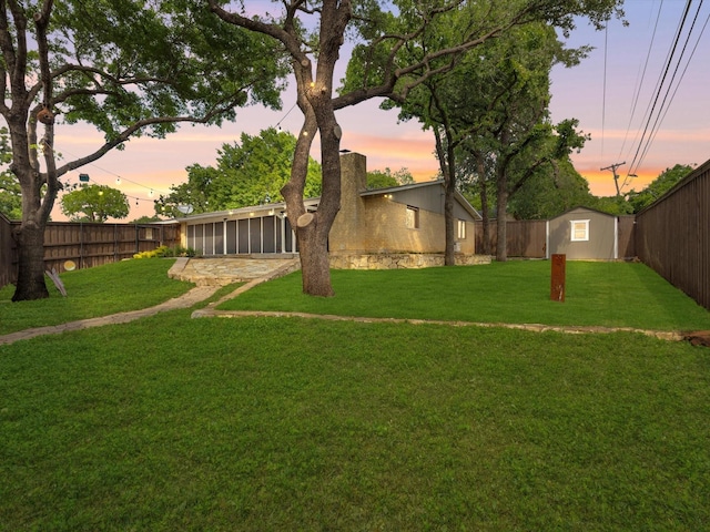 view of yard with an outbuilding, a sunroom, a storage unit, and a fenced backyard
