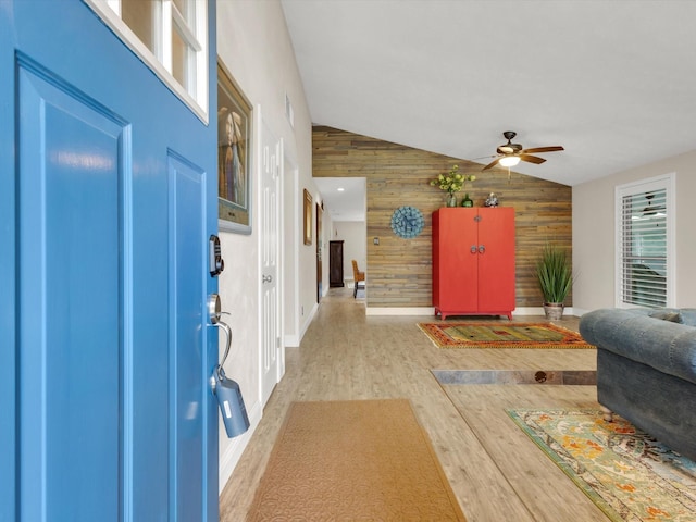 entrance foyer with wood finished floors, wood walls, ceiling fan, baseboards, and lofted ceiling