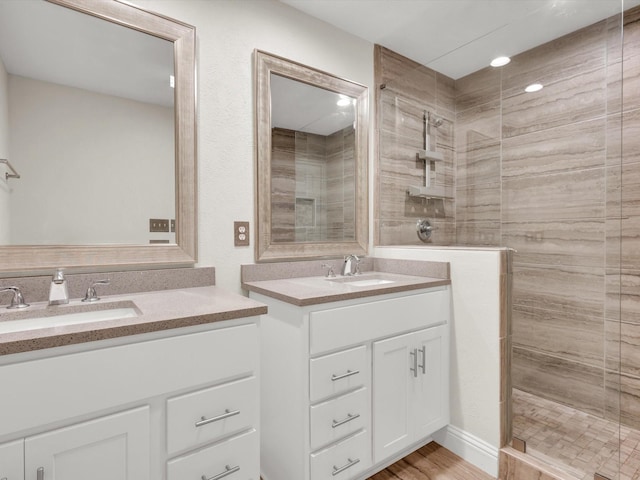full bathroom featuring two vanities, walk in shower, and a sink