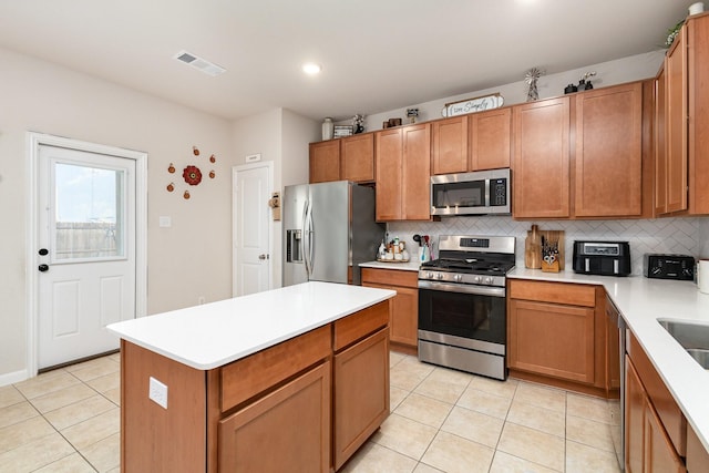 kitchen featuring visible vents, light tile patterned floors, stainless steel appliances, and decorative backsplash