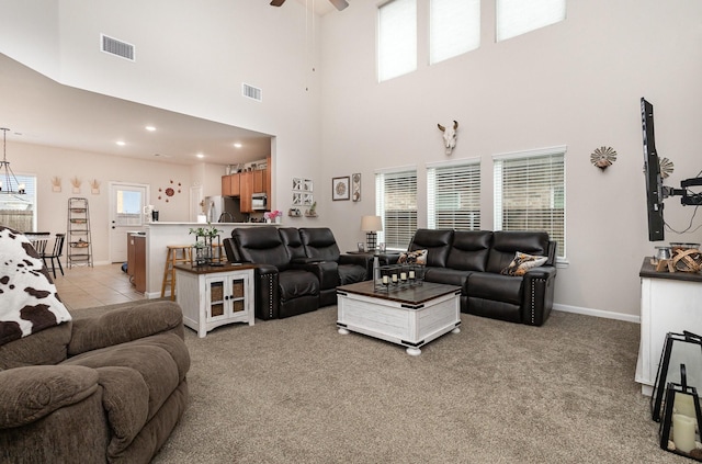 living room featuring a high ceiling, visible vents, and light colored carpet