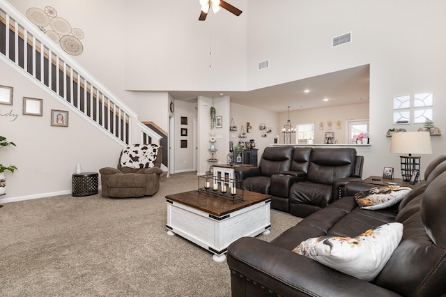 living room featuring carpet flooring, stairway, visible vents, ceiling fan, and a high ceiling