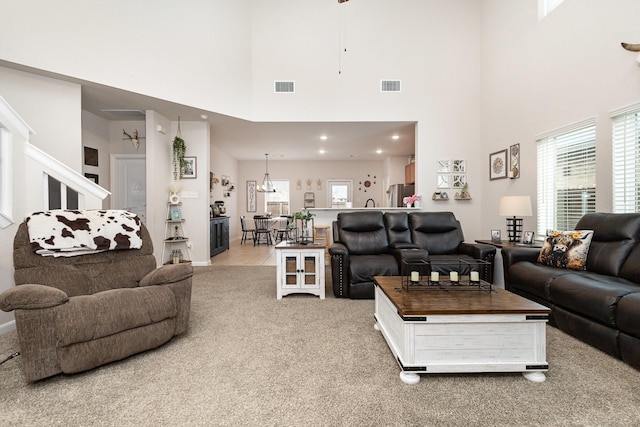 living room with a towering ceiling, visible vents, light colored carpet, and baseboards