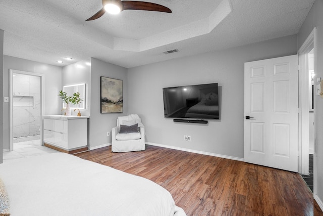 bedroom featuring baseboards, visible vents, wood finished floors, and a textured ceiling