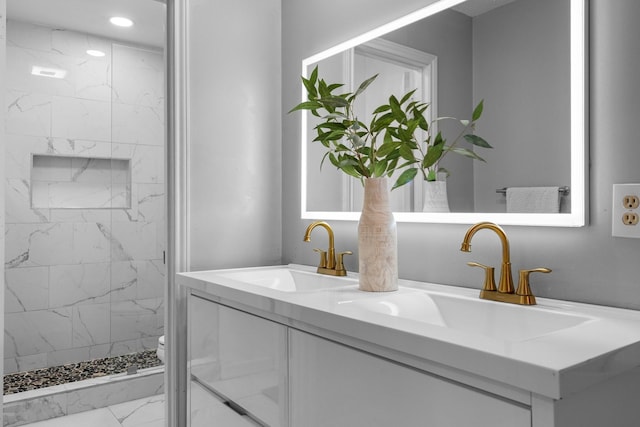 bathroom with a marble finish shower, marble finish floor, a sink, and double vanity