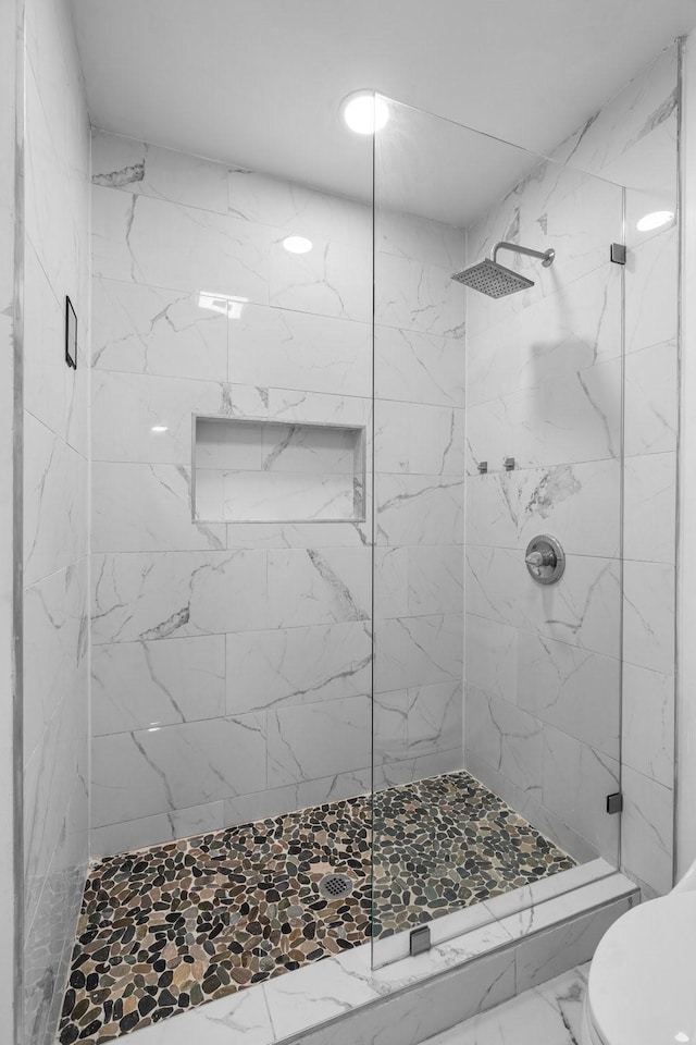 full bath featuring toilet, marble finish floor, and a stall shower