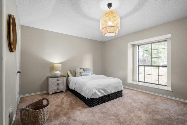 carpeted bedroom featuring a textured ceiling and baseboards