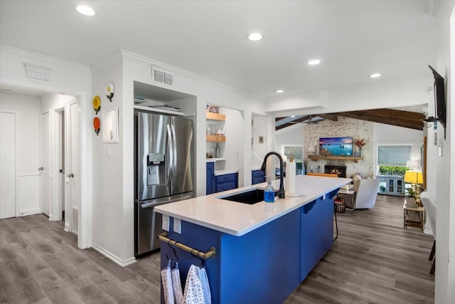 kitchen with a sink, lofted ceiling with beams, blue cabinetry, visible vents, and stainless steel fridge with ice dispenser