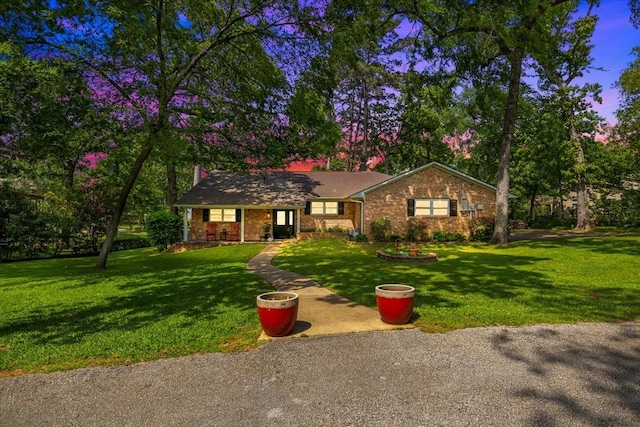 ranch-style home featuring a front yard and brick siding