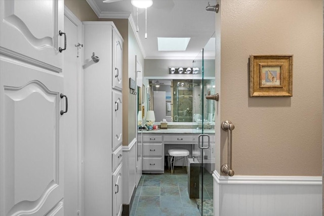 bathroom featuring a shower stall, ceiling fan, ornamental molding, vanity, and a skylight