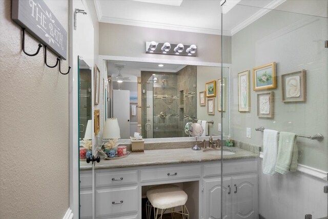 bathroom featuring a ceiling fan, ornamental molding, a shower stall, and vanity